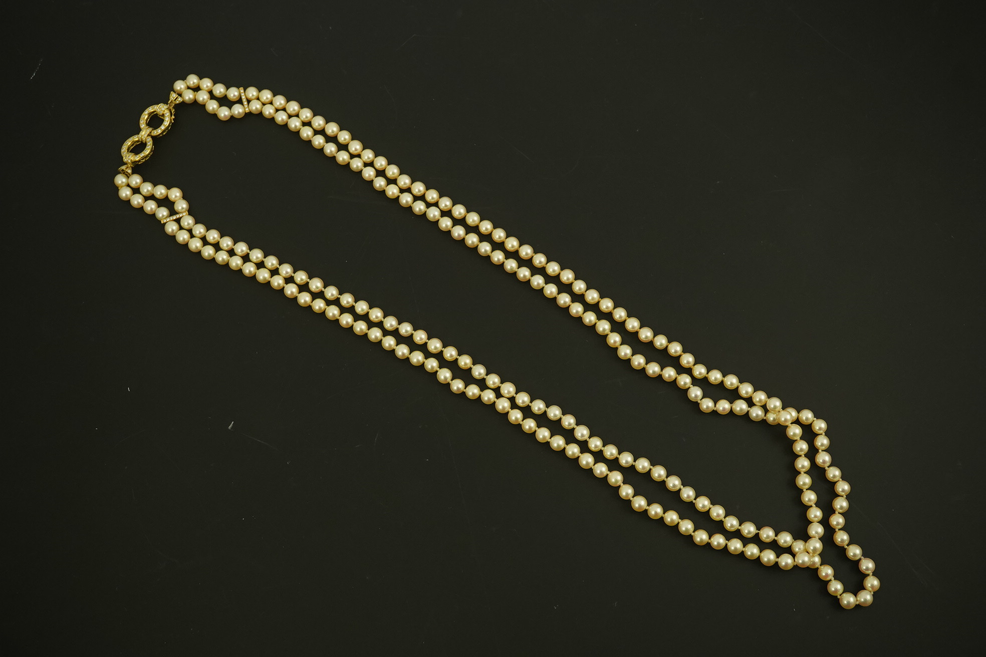 A modern double strand cultured pearl necklace, with 18k gold and diamond set twin ring clasp